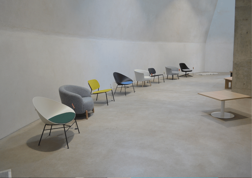 Verschiedene Lounge-Sessel vor einer grauen Beton-Wand