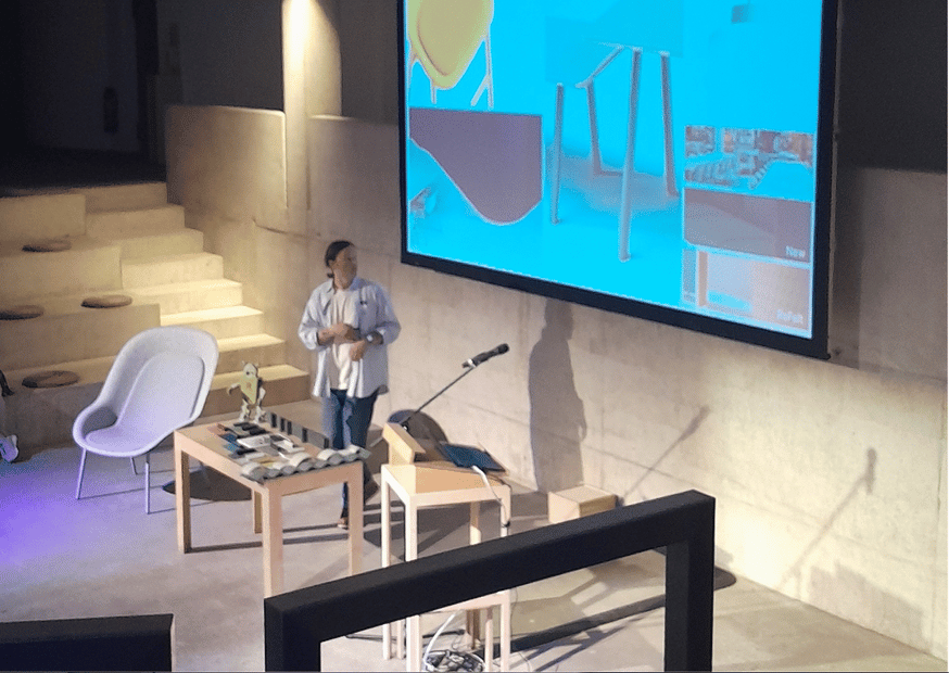 Vortragssituation mit Möbel-Exponaten, Präsentation auf Leinwand und Speaker 